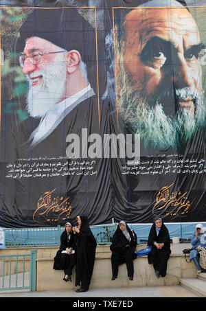 Iranian women sit in front of the pictures of Iran's late leader Ayatolah Khomeini (R) and Iran's current leader Ayatolah Khamenei during the International Koran Exhibition at the Imam Khomeini Grand Mosque during the holy month of Ramadan on August 16, 2010 in Tehran, Iran.   UPI/Maryam Rahmanian Stock Photo