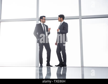 two businessmen standing near a large office window Stock Photo