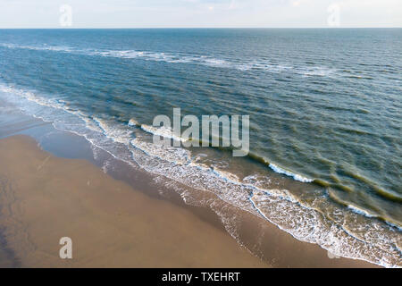 Drone view on the coastline and surf on the sandy beach of the island of Juist in the North Sea Germany.