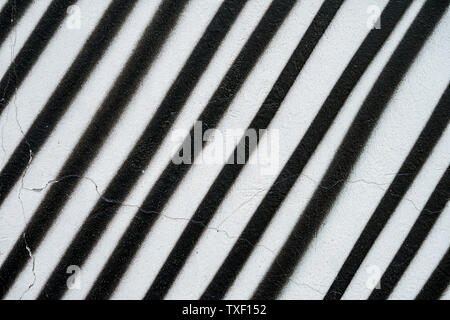 Diagonally painted surface of wall in black and white color, as graffiti. Old concrete surface with peeling paint. Graphic grunge texture of wall Stock Photo