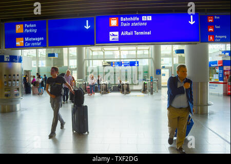 FRANKFURT AM MAIN, GERMANY - AUGUST 29, 2018: People with luggage exiting Frankfurt airport, Info board with direction signs above, Frankfurt am Main, Stock Photo