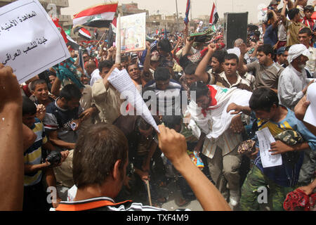 Iraqi Shiite Moslems protesters burn an American flag after Friday prayers in the Baghdad suburb of Sadr City on June 6, 2008. Thousands of Shiite Moslem, loyal to the radical cleric Muqtada al Sadr, protested against a security agreement between the Iraqi government and the United States that could prolong the presence of U.S. troops in Iraq. Protesters burned flags and marched through the streets. (UPI Photo/Ali Jasim) Stock Photo