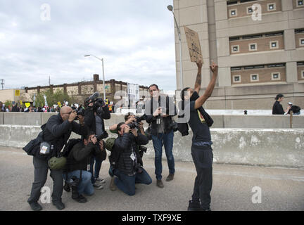 Photographers take pictures of Caron Carroll, 18, of Baltimore as he blocks an off ramp to rt 83 during the Black Lives Matter May Day Action Protest to show support for Freddie Gray and all arrested protesters, in Baltimore, Maryland, May 1, 2015. Baltimore City state's attorney Marilyn Mosby, announced earlier today that the death of Freddie Gray was a homicide and said the six arresting officers will be charged. Gray, 25, who was arrested on April 12, died a week later in the hospital from spinal cord injury he received while in police custody. Photo by Kevin Dietsch/UPI Stock Photo