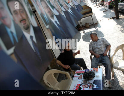 Lebanese men chat beneath campaign posters for Saad Hariri, son of the popular slain ex PM Rafik Hariri in Beirut on May 28, 2005, the evening before parliamentary elections are due to take place. The elections will be the first in thirty years to be held without the presence of Syrian troops in Lebanon.  It is typical of Lebanese politics that a relative of a popular leader should ride the wave of popularity into public office. (UPI Photo/Stewart Innes) Stock Photo