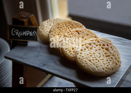 Hot toasted English crumpets arranged in a line as part of a hotel breakfast buffet