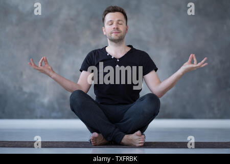 Yoga male beginner practicing yoga sitting in pose and meditates Stock Photo