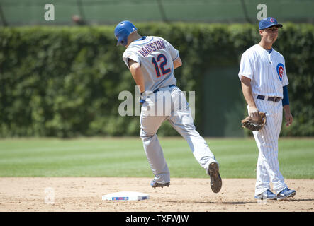 New York Mets' Scott Hairston (L) rounds the bases as Chicago Cubs second baseman Darwin Barney stands on the field after Hairston hit a grand slam scoring Ruben Tejada, David Wright and Lucas Duda leave the ballpark during the sixth inning at Wrigley Field on June 27, 2012 in Chicago.    UPI/Brian Kersey Stock Photo