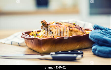 Roasted whole chicken with potatoes in baking dish. Tasty food at home on the kitchen counter Stock Photo