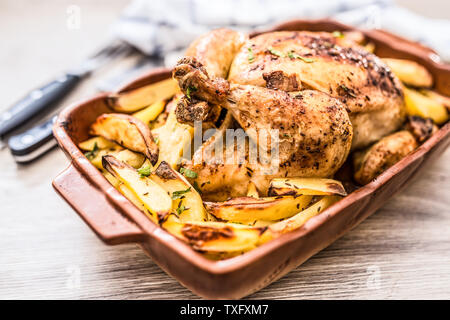 Roasted whole chicken with potatoes in baking dish. Tasty food at home on the kitchen counter