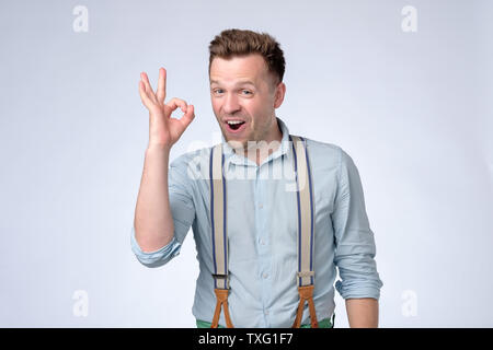 Happy young man in shirt and suspenders gesturing OK sign Stock Photo