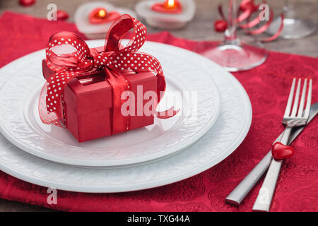 Place setting and gift on holiday table . Stock Photo