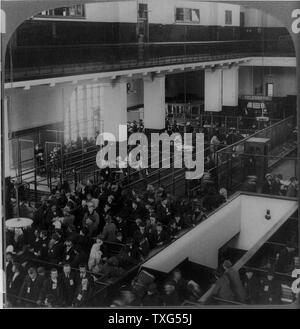 Immigrants just arrived in the USA from Europe waiting to be processed in the immigrant building : Ellis Island, New York. Stock Photo