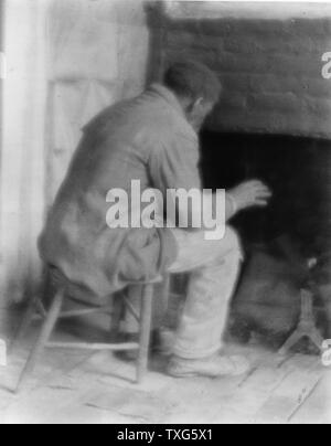 African American, possibly a former slave, sitting warming himslef by the fire in his room Stock Photo