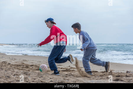 Two young kids playing football on the beach in Corfu Greece. Stock Photo