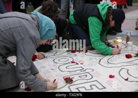 People sign a banner at a candlelight vigil held at Boston Common in Boston, Massachusetts on April 16, 2013.  The vigil is in response to the bombings on Boylston Street near the finish line of the Boston Marathon Monday afternoon killing 3 and injuring 150.    UPI/Matthew Healey Stock Photo