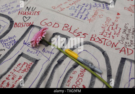 A flower rests on a signed banner at a candlelight vigil held at Boston Common in Boston, Massachusetts on April 16, 2013.  The vigil is in response to the bombings on Boylston Street near the finish line of the Boston Marathon Monday afternoon killing 3 and injuring 150.    UPI/Matthew Healey Stock Photo