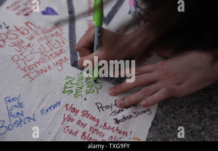 People sign a banner at a candlelight vigil held at Boston Common in Boston, Massachusetts on April 16, 2013.  The vigil is in response to the bombings on Boylston Street near the finish line of the Boston Marathon Monday afternoon killing 3 and injuring 150.    UPI/Matthew Healey Stock Photo