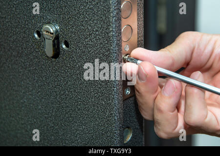 Man fixing the door with screwdriver. Door lock repair. Stock Photo