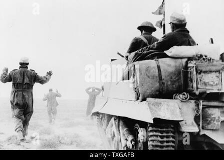 German infantry surrendering to men of New Zealand Bren carrier unit. A wounded prisoner can be seen riding in the back of the carrier, Jan, 1942 Stock Photo