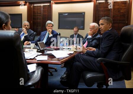 president Barack Obama in the White House situation room with administration officials seated left to right: Eric Holder; John Kerry and Jo Biden Stock Photo