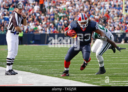 New York Jets running back Thomas Jones (20) is tackled at midfield by  Buffalo Bills cornerback Kiwaukee Thomas (25) and linebacker Angelo Crowell  (55) during the third quarter at Ralph Wilson Stadium