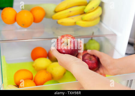 Woman getting red apples from fridge. Close up. Stock Photo