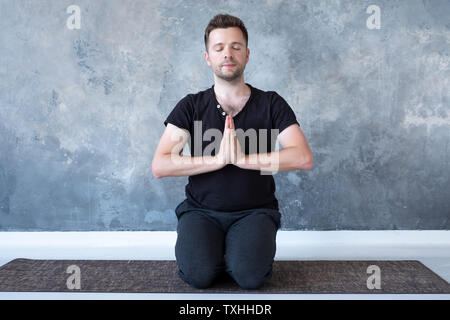 Young sporty man practicing yoga lesson sitting in vajrasana pose Stock Photo
