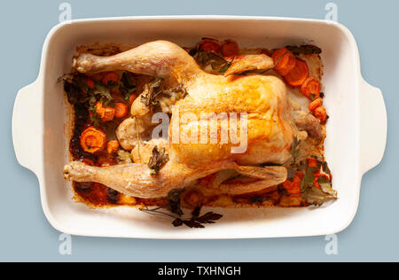 Oven-roasted chicken with vegetables in a baking dish. Top view image on light blue gray background. Stock Photo