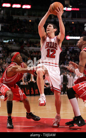 Chicago Bulls' Kirk Hinrich (12) goes up for a shot as Houston Rockets' Rafer Alston, left, and Tracy McGrady during the second overtime on January 20, 2006, in Chicago. Hinrich missed the shot. The Rockets won 109-108 in double overtime. (UPI Photo/Brian Kersey) Stock Photo