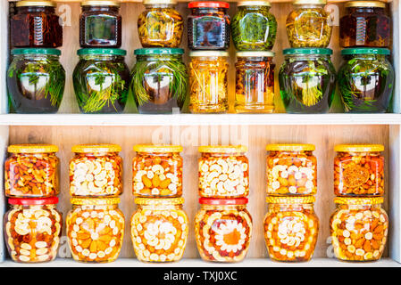 Jars with honey, nuts and natural herbs for sale on shelves Stock Photo