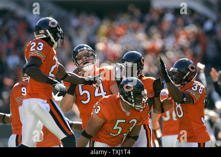 Chicago Bears linebacker Brian Urlacher (54) hands the ball to center Olin  Kreutz (57) and points to the scoreboard after making an interception on a  pass thrown by Carolina Panthers quarterback Jake