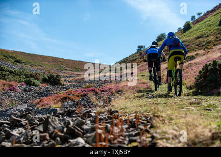 Two men ride mountain bikes up a path from Porlock Bay on the North Somerset Coast towards Selworth Beacon Stock Photo