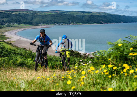 Two men ride mountain bikes up a path from Porlock Bay on the North Somerset Coast towards Selworth Beacon