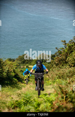 Two men ride mountain bikes up a path from Porlock Bay on the North Somerset Coast towards Selworth Beacon