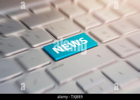 latest internet news concept with a blue button on computer keyboard. blue button on grey silver laptop keyboard. blurred in motion background. Stock Photo