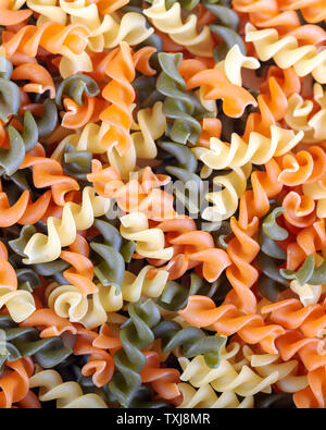 Colorful raw rutini pasta with vegetables like as background.