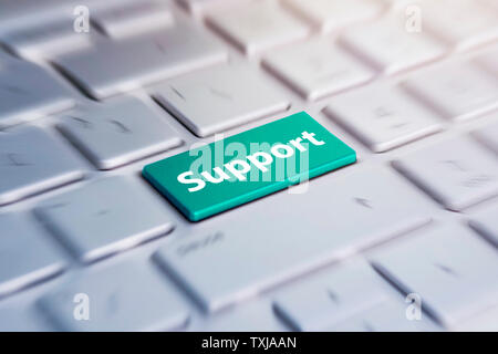 Blue support keyboard button. Green Button on grey Computer Keyboard. blurred in motion background. Stock Photo