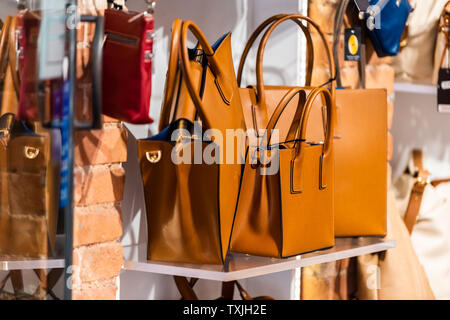 Many leather purse bags in Siena Italy with orange brown color hanging on display in shopping street market in city Stock Photo