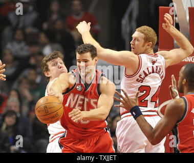 New Jersey Nets forward Kris Humphries C passes the ball as Chicago Bulls center Omer Asik L and forward Brian Scalabrine defend during the second quarter at the United Center on January 23 2012 in Ch...