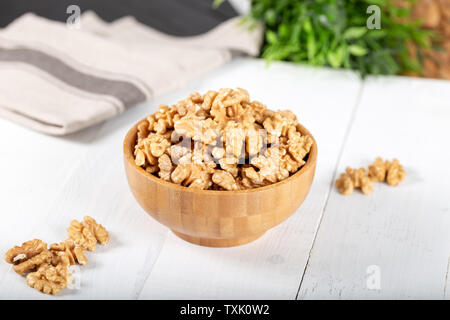 Walnut kernels in a wooden bowl on white background. Stock Photo