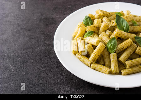 Penne pasta with pesto sauce on black background. Copyspace Stock Photo