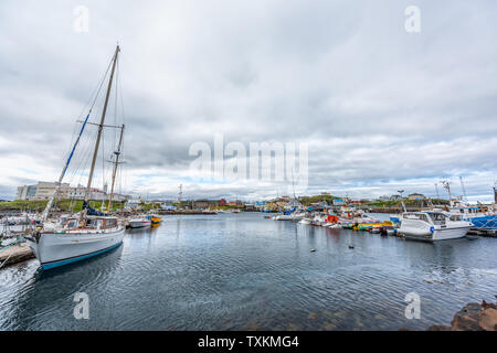 Stykkisholmur, Iceland - June 18, 2018: Town on cloudy day and cityscape skyline of small fishing village on Snaefellsnes peninsula with boat