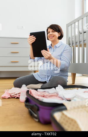 pregnant woman with tablet pc packing hospital bag Stock Photo