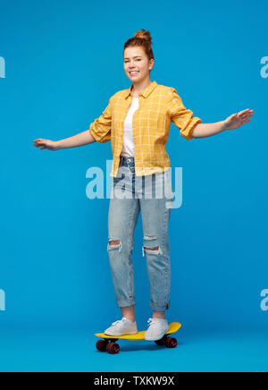 red haired teenage girl riding on short skateboard Stock Photo