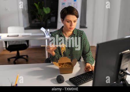 businesswoman eating and working at night office Stock Photo