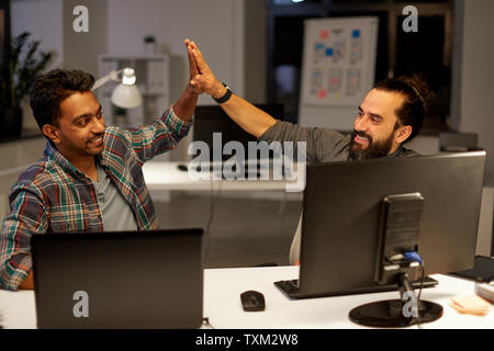 creative team making high five at night office Stock Photo