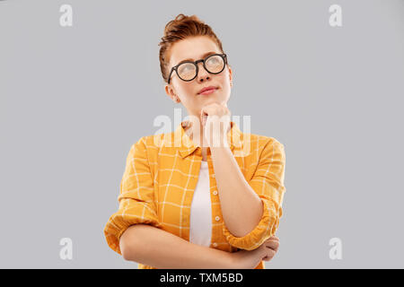 thinking redhead teenage student girl in glasses Stock Photo