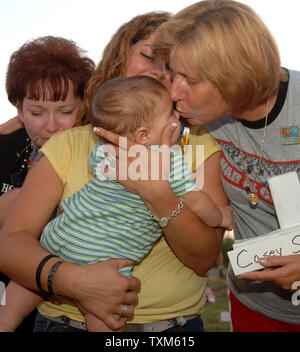 Peace demonstrator Cindy Sheehan (R) comforts Susan House, Melanie House and eight-months-old James House during a gathering at sunset at Camp Casey II near U.S. President George W. Bush's Crawford, Texas ranch on Aug. 24, 2005. Sheehan, whose son Casey died in Iraq in 2003, has been camped out near the ranch hoping to meet with the President for a second time and has drawn hundreds of peace demonstrators to the site. John house died in Iraq on Jan. 26, 2005, leaving his mother Susan, wife Melanie and James, a son he never met.  (UPI Photo/Roger L. Wollenberg) Stock Photo