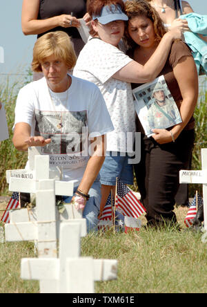 Cindy Sheehan puts her hand on her son's cross after placing his boots at his cross at Camp Casey II near U.S. President George W. Bush's Crawford, Texas ranch on Aug. 25, 2005. Sheehan, whose son Casey died in Iraq in 2003, has been camped out near the ranch hoping to meet with the President for a second time and has drawn hundreds of peace demonstrators to the site. Behind Sheehan are Susan and Melanie House (l to r), whose son and husband, respectively, John House died in Iraq on Jan. 26, 2005.     (UPI Photo/Roger L. Wollenberg) Stock Photo