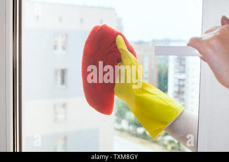 hand cleans window glass of urban apartment house by orange rag Stock Photo